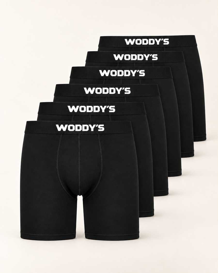 Sechs schwarze Boxershorts mit langem Bein und weißem WODDY’S-Logo, versetzt vor warmem Off-White.